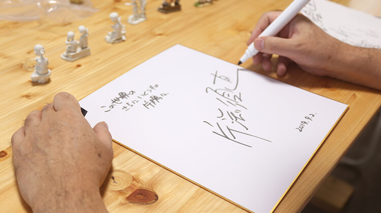 インタビューの様子04 サインを書く片渕須直監督の手元の画像